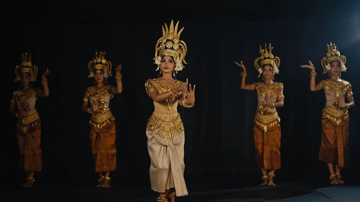 Five dancers in gold costumes on stage