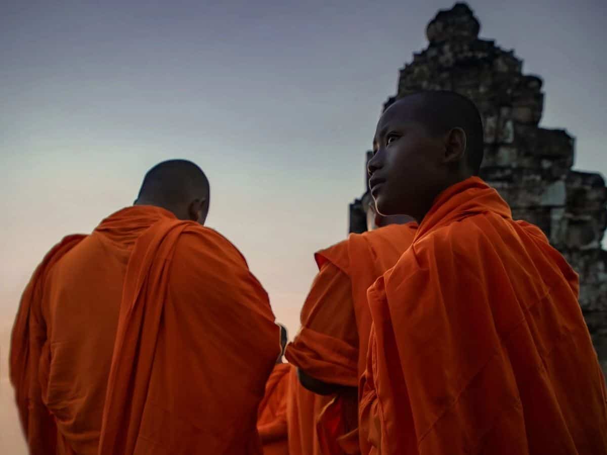 Two monks at sunset in front of a stone temple